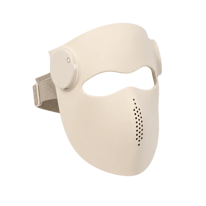 A beige full-face sleep mask with an integrated side sleep button and a strap, shown on a white and gray checkered background.